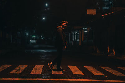 Man standing on wet street at night