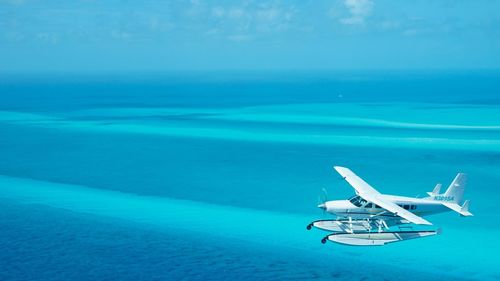 Airplane flying over sea against blue sky