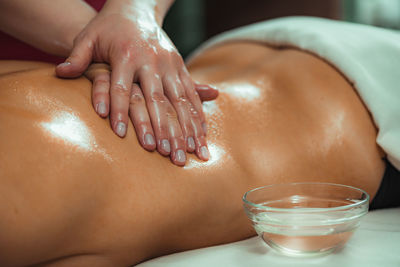 Massaging with massage oil, hands of a female massage therapist massaging a female client