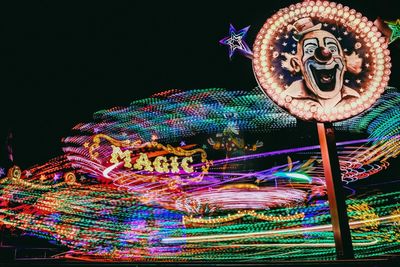 Close-up of illuminated ferris wheel against sky at night