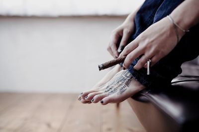 Close-up of woman hand holding burning cigar at home