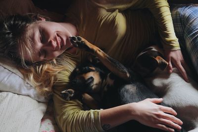 Young woman with dogs relaxing on bed at home