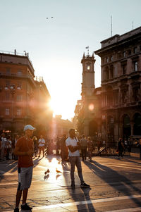 People walking on street in city at sunset