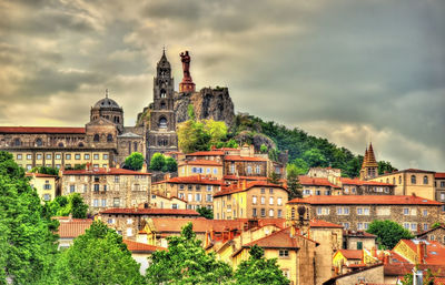 View of buildings in city against cloudy sky