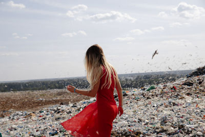 Woman walking amidst garbage against sky