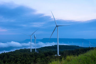 Wind turbines on field against sky