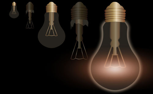 Close-up of illuminated light bulb against black background