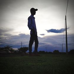 Silhouette man standing on field against sky during sunset