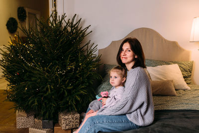 Portrait of young woman with christmas tree at home