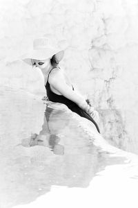 Young woman in bikini hat against water