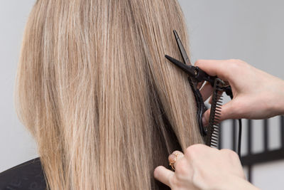 Cropped hands of hairdresser cutting woman hair at salon