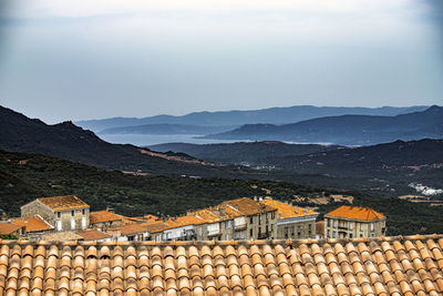 Stack of roof and building by mountains against sky