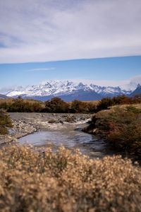 Scenic view of lake by snowcapped mountain against sky