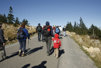 Rear view of people walking on road against clear sky