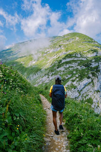 Rear view of woman walking on trail against sky