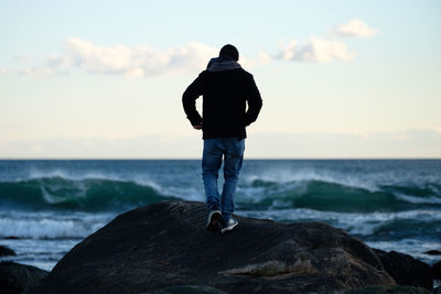 Rear view of man looking at sea against sky