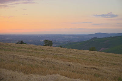 Scenic view of field against sky at sunset