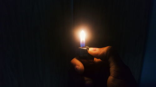 Holding cigarette lighter with flame over black background