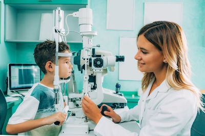 Side view of female ophthalmologist checking eyesight of boy in hospital