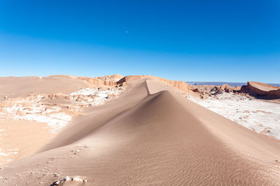 Sand dunes in desert against clear blue sky