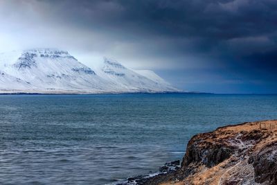 Scenic view of sea and snowcapped mountains against sky