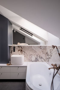 Bathroom in a building with bathtub, sink, mirror, and wood fixtures