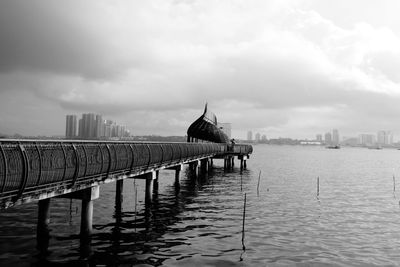 Bridge over river by buildings in city against sky
