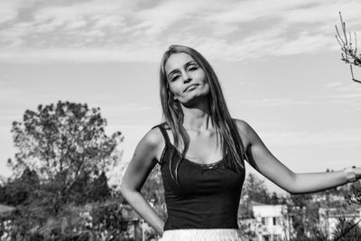 Portrait of smiling young woman standing against sky