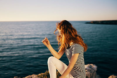 Woman by sea against sky