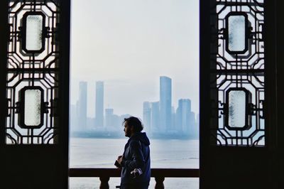 Side view of young man standing by river in balcony