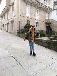 Full length of woman walking on footpath against building in city