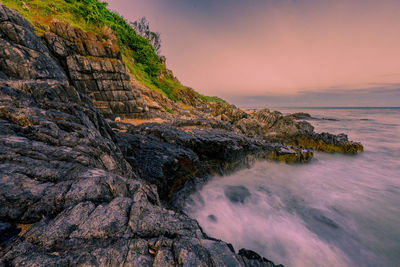 Rock formation on beach against sky during sunset