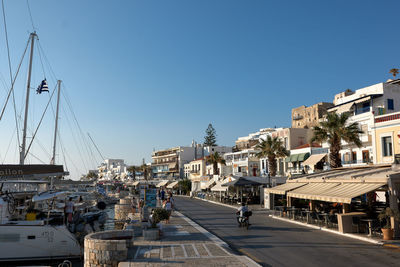 Cars on road by buildings against clear sky