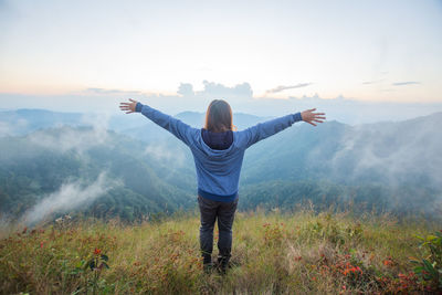 Rear view of man standing on mountain against sky