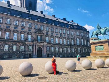 Young woman standing by sphere structures on walkway in city