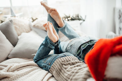 Low section of woman lying on sofa at home