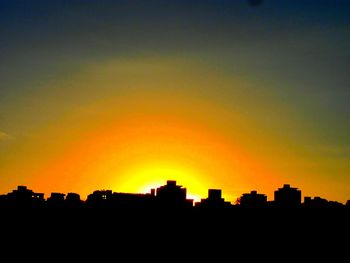 Silhouette cityscape against sky during sunset