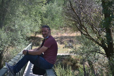 Side view of young man sitting in forest