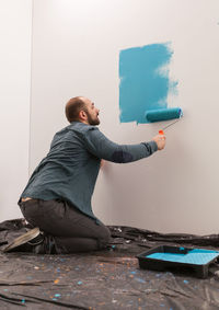 Side view of man looking at camera against wall