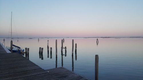 Wooden posts on jetty by sea against clear sky