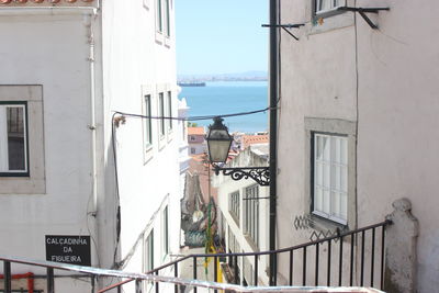 Buildings by sea against clear sky seen through balcony