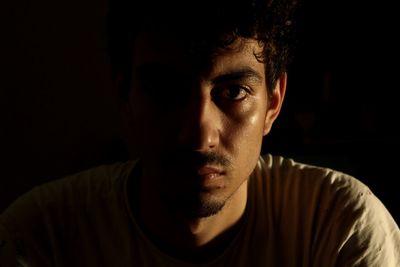 Close-up portrait of young man against black background