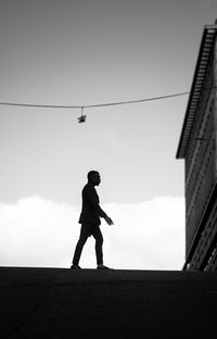 Low angle view of silhouette woman walking on field against clear sky