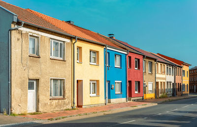 Residential building by road against blue sky