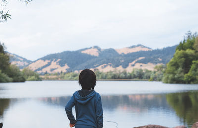 Rear view of child standing against lake