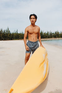 Portrait of shirtless man sitting on beach