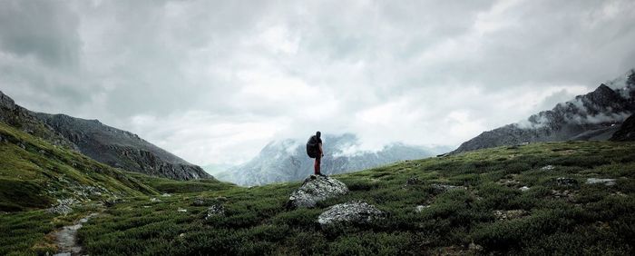 Man standing on mountain against cloudy sky