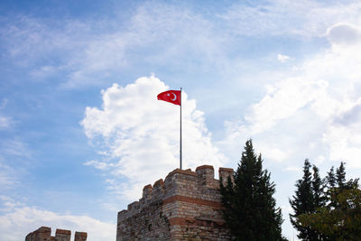 Low angle view of flag by building against sky