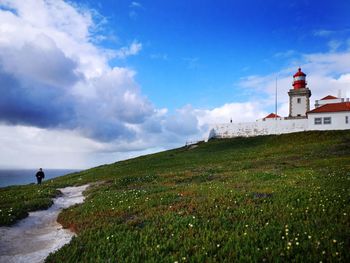 Lighthouse by building against sky