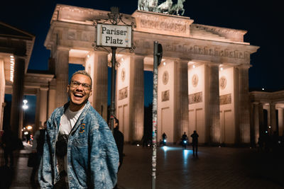 Portrait of smiling man standing in city at night